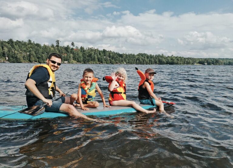 a father and three kids in a stand up padle in the lake